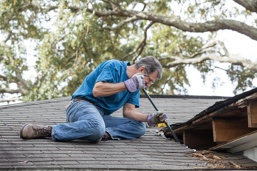 Man using a crowbar to perform a DIY Dublin roof repair project.
