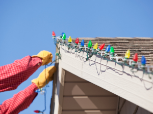 Homeowner decorating roof with holiday lights